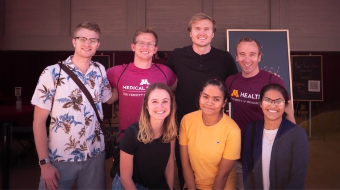 Image of Dr. McGovern and medical residents, fellows and students smiling for a photo in front of the U of M's "Driven to Discover" building at the Minnesota State Fair.